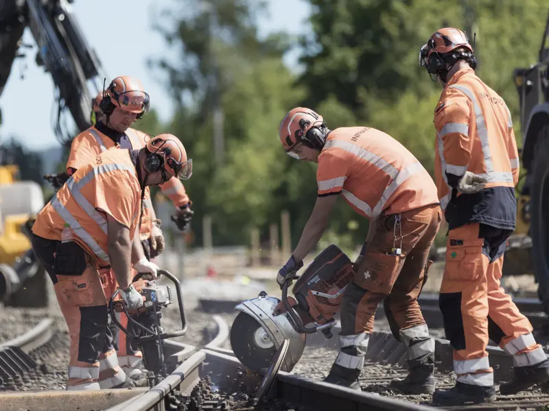 Flera stycken järnvägstekniker som kapar räls