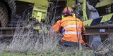  Bild på en orangeklädd järnvägstekniker som inspekterar en spårbytesmaskin