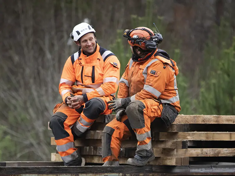 Två anställda på Infranord som pratar medan en spårbytesmaskin står still